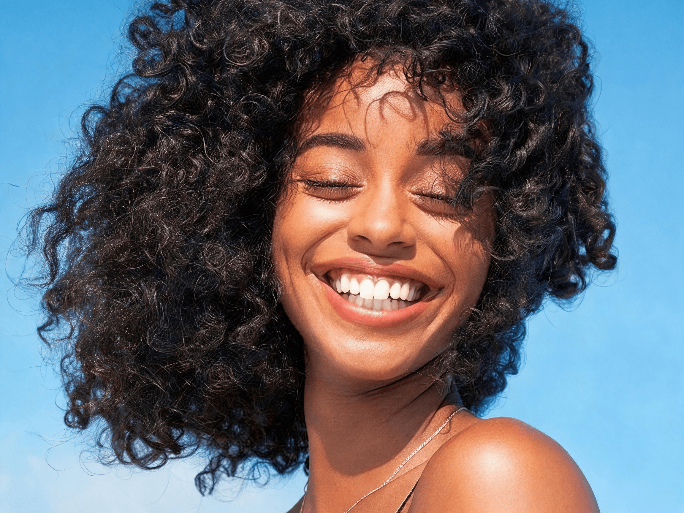 Smiling woman with voluminous curls against a blue background